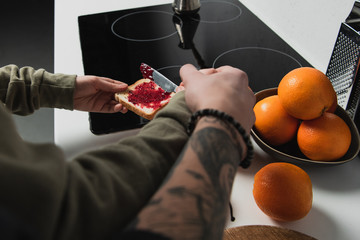 partial view of couple preparing toasts with jam during breakfast in kitchen