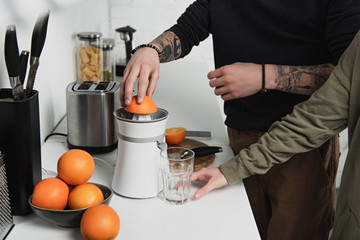 partial view of couple preparing orange juice during breakfast in kitchen