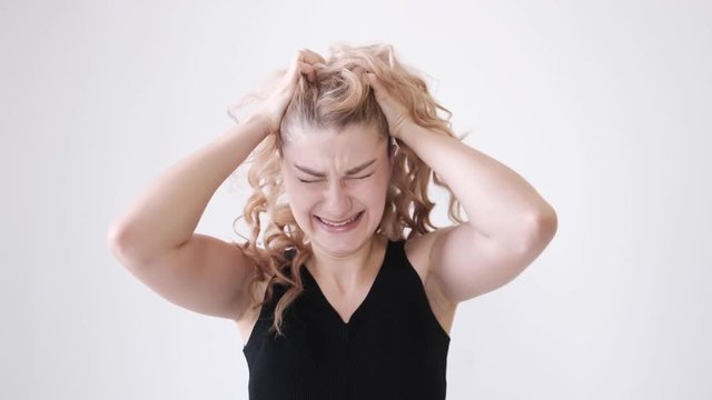 Closeup of young stressed redhead girl screaming isolated on white background