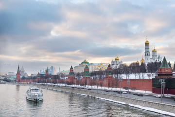 Fototapeta premium Kremlin embankment of the Moscow river, boat on the river at sunset, view of Moscow at sunset in winter