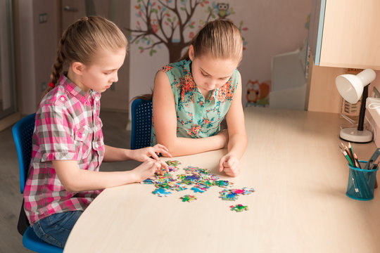 Two little girls solving puzzle together