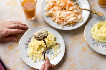 cutlet on a fork in hand, mashed potatoes on a plate
