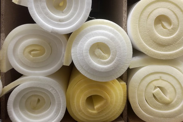 Rolls white and yellow foam rubber building material texture. Polystyrene sealing foam surface background.