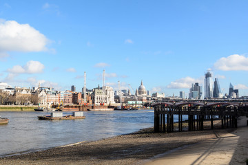 River Thames in London at low tide with exposed sand. View of the city in the background