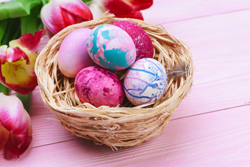 Beautiful Easter composition with decorated eggs and flowers on pastel wooden background