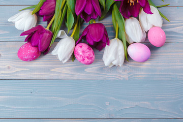 Easter eggs with tulips on blue wooden background