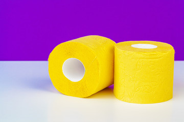 Minimalistic composition of bright yellow toilet paper rolls on purple background