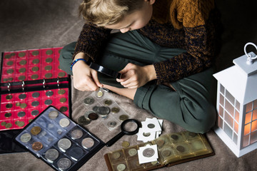 cute boy numismatist collects old coins, an album with coins