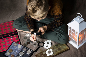 cute boy numismatist collects old coins, an album with coins