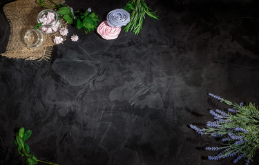 Heap of sweet meringue mixed with flowers on dark background. Top view with copy space