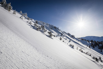 Winter am Berg in den Alpen mit Sonne und blauem Himmel