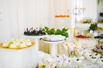 Delicious and tasty dessert table with cupcakes shots at reception closeup