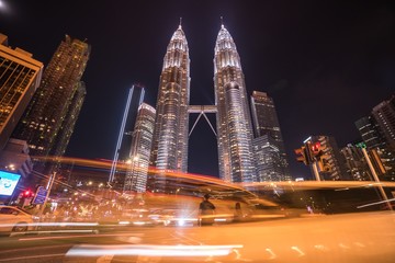 Naklejka premium People lost in hectic traffic in front of Petronas Towers at night