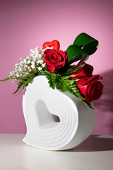 Bouquet of red roses in a vase in the shape of a heart