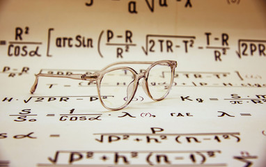 Mathematical background, handwritten formulas brown.
