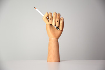 front view of wooden hand holding a white pencil