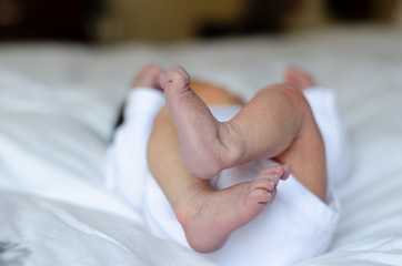 Newborn baby feet, baby lying on the bed at home