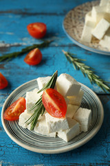 Plate with tasty feta cheese and tomato on table