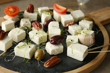 Tasty feta cheese with olives, tomato and pecan nuts on slate plate