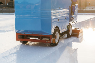 Cropped front outdoor photo of special machine leveling ice rink/ ice preparation, maintenance machine clean and pours ice before the game, ice resurfacer at work, public skating rink, hockey stadium.