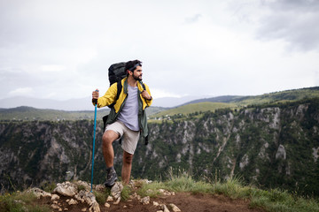 Obraz premium Young man traveling with backpack hiking in mountains