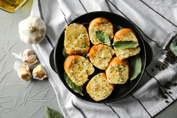 Pan with tasty garlic bread on table