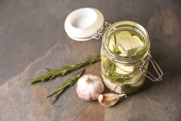 Glass jar with tasty feta cheese, olive oil and garlic on table