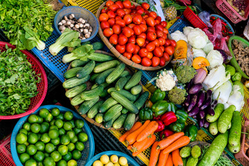 Vegetables for sale, including cucumber, tomatoes, carrots, and lime, in a market stall in the old town of Hoi An, central Vietnam.