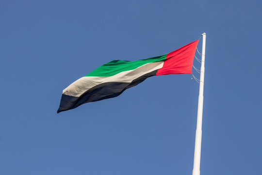 United Arab Emirates flag waving on Blue background, long shot, Abu Dhabi, Dubai