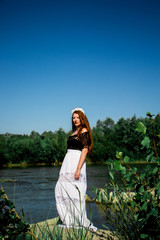 Young redhead woman in dress on the rock around the water and green leaf