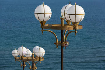 two street lamps with round lights on the background of the sea, concept