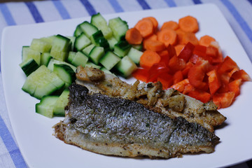 Roasted trout and chopped fresh vegetables, red pepper, carrot and cucumber. Healthy food. Roasted fish.