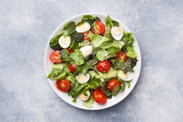 Fresh salad with tomatoes and quail eggs and lettuce.