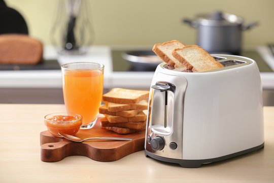Toaster with bread slices and glass of juice on table