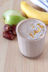 Healthy organic date, banana and apple milk smoothie powdered shredded coconut and orange zest. Fresh diet breakfast. Wooden background. Selective focus.