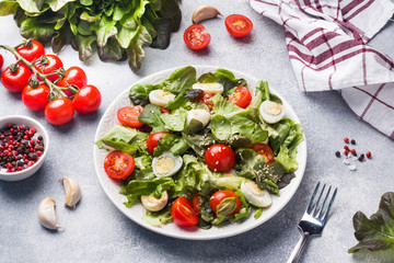 Fresh salad with tomatoes and quail eggs and lettuce.
