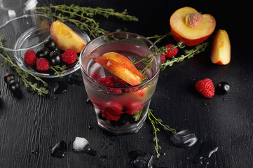 Raspberry thyme gin and tonic cocktail with blackcurrant and peaches