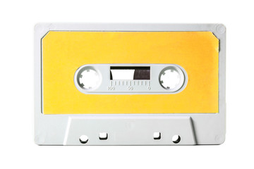 An old vintage cassette tape from the 1980s (obsolete music technology). White-grey plastic body and warm yellow label, isolated on white.