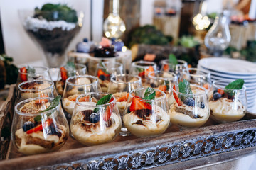Delicious desserts parfait with blueberries and strawberries on a beautifully decorated table with wooden elements