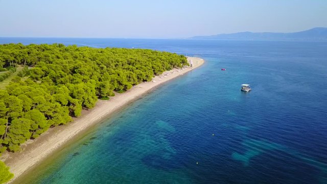 Aerial bird's eye view video taken by drone of exotic seascape and sandy beach with turquoise clear waters and pine trees, Gregolimano, North Evoia island, Greece