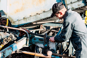 Farmer mechanic repairing agricultural machinery. Male hand holding wrench, repairing combine...