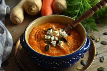 Sweet potato cream soup in a rustic bowl on a wooden background