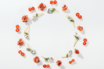 top view of sliced pears with blue cheese and rosemary twigs near tasty prosciutto and cherry tomatoes on white background