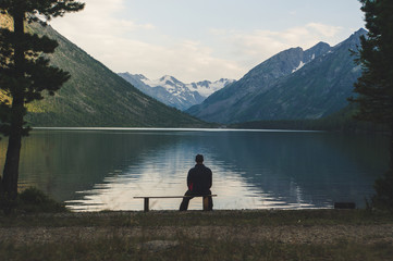 Senior is seating alone on the beach bench in overcast weather