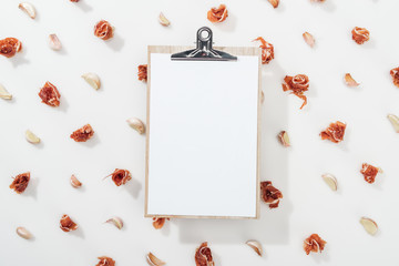 top view of clipboard among prosciutto and garlic cloves