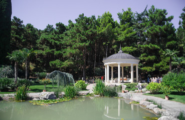 Fototapeta na wymiar Rotunda in antique style in an olive grove near the pond