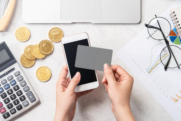 Naklejka na ściany i meble A woman is doing a online payment with card and smartphone isolated on a modern marble office table, mock up, top view, copy space, flat lay, lifestyle, close up