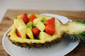 Strawberries, kiwi and melon served in pineapple. On white plate. Party serving
