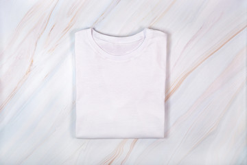 Plain white tshirt on marble background. Blank white t-shirt on marble texture with natural pattern. Flat lay