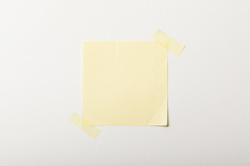 yellow blank paper with sticky tape on white background
